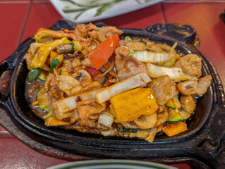 Chinese style fried chicken: Chinese style chicken fried with vegetables and served on black iron, hot plate