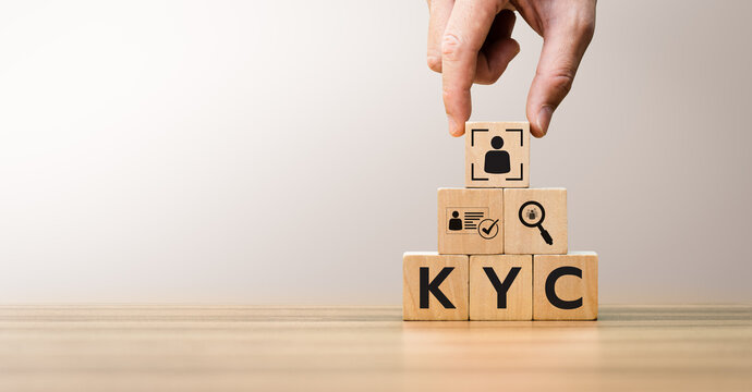 Hand arranging wooden blocks with KYC icons, representing Know Your Customer process, digital identity verification, compliance, anti-fraud measures, and customer authentication concepts.