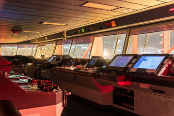 Night view of the control console on the navigational bridge of the cargo container ship berthed in...