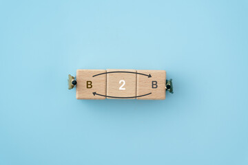 Fototapeta premium Business concept success process. wooden cube blocks with b2b text and top view of miniature businessman on blue background, including copy space