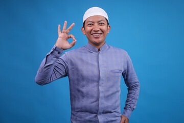 Portrait OF Young Asian Muslim Man Showing OK Sign On Blue Background