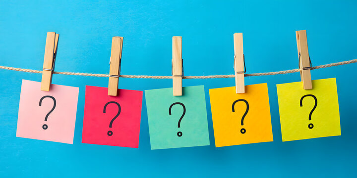 Colorful sticky notes with question marks hanging on a rope with clothespins, symbolizing uncertainty, brainstorming, or decision-making