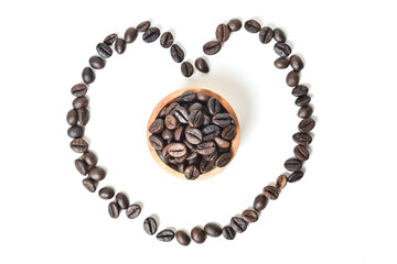 Top view of Roasted Coffee beans in little wooden bowl isolated on white background. Clipping path. Roasted coffe beans in heart shape, love coffee concept, flat lay.