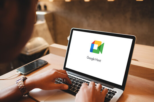 Bangkok, Thailand. Feb 28, 2025; Person using a laptop displaying the Google Meet logo while sitting at a workspace with a smartphone nearby.