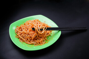 a spaghetti served on a green plate isolated on a black background