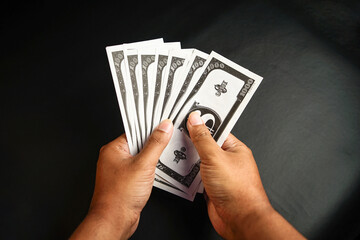 Close up of an Asian man hand with tan skin holding dollar money, fake money