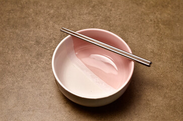 Pink And White Bowl With Metal Chopsticks on Stone Surface