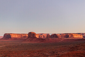 Monument Valley glows orange as the sun starts to set in the late evening.