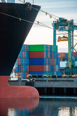 The bow of a ship docked next to an unloading terminal in late afternoon