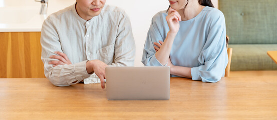 自宅のリビングでパソコンを見る夫婦