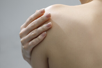 female hand on naked shoulder close up, beauty skin care concept