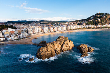 Obraz premium Picturesque aerial view of Blanes cityscape on Mediterranean coast overlooking symbol of city, Sa Palomera Rock and San Juan hill with tower of medieval castle on sunny day, Catalonia, Spain..