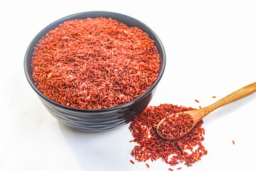 uncooked brown rice in bowl and spoon isolated on white background