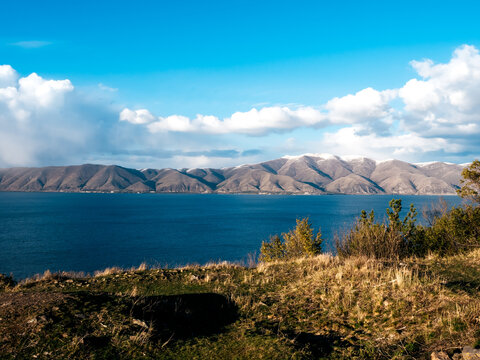 Beautiful autumn view with blowing wind at Lake Sevan, landscape on the hill near Sevanavank Monastery, many mountain on blue water lake and blue sky and white clouds background Armenia country.