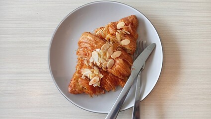 Flaky butter croissant topped with sliced almonds and dusted with powdered sugar.