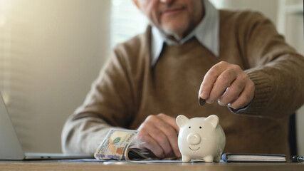 Saving money investment for future. old man hand putting money coins into a piggy bank. investment, money, annuity insurance, saving for retirement and pension fund Individual retirement account.