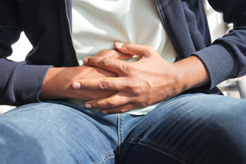 Man experiences stomach discomfort while seated outdoors