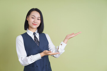 Professional young woman presenting on a green background with a confident smile for a promotional event or business setting