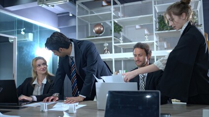 In the conference room, a group of businesspeople are discussing the follow-up meeting and the...