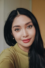 Fototapeta premium Beautiful young Asian woman wearing contact lenses and full make up taking a selfie.