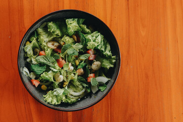 Thai prawn salad with fresh green lettuce and cucumbers, tomatoes and sesame seeds.