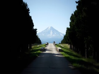 "Long Straight Road Leading to Snow-Capped Mountain Under Clear Blue Sky - Scenic and Serene Landscape Image"