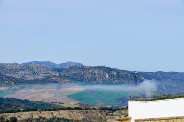 mountainous landscape with blue sky and a cloud of smoke from a fire with a white text wall