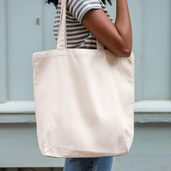 Tote bag mockup. Closeup African American woman carrying white cotton fabric canvas blank totebag on blue green background