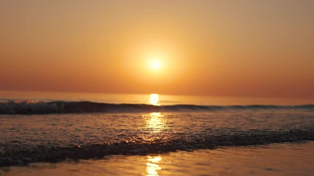 4K Slow motion shot of a beautiful sunset at Mandvi Beach in Kutch, Gujarat, India. Sea waves and entire sea becomes golden in colour during the sunset. Orange colored sea. Natural sea background.