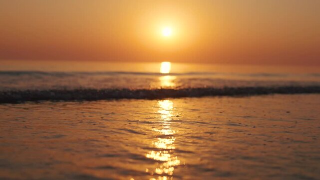 4K Slow motion shot of a beautiful sunset at Mandvi Beach in Kutch, Gujarat, India. Sea waves and entire sea becomes golden in colour during the sunset. Orange colored sea. Natural sea background.