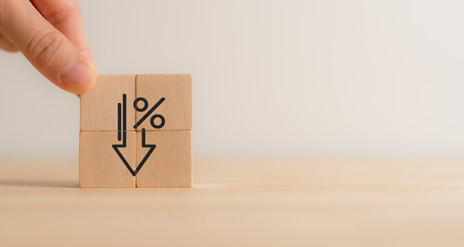 Financial decline and percentage decrease concept. Wooden blocks with downward arrow with a percentage sign, representing financial decline, economic downturn, decreasing interest rates, deflation.