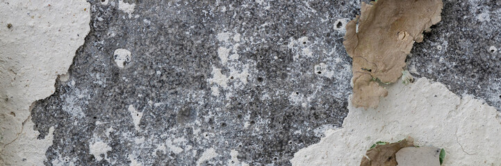 Peeling paint on the wall. Panorama of a concrete wall with old cracked flaking paint. Weathered rough painted surface with patterns of cracks and peeling. Wide panoramic texture for grunge background