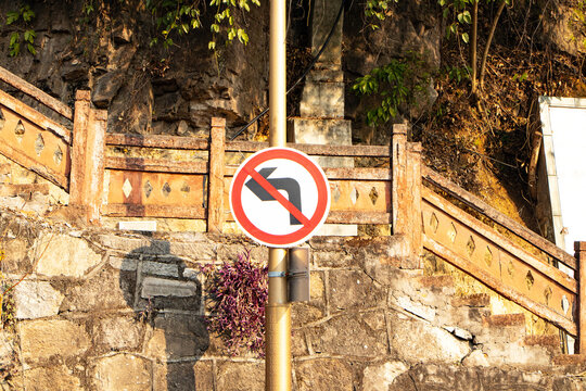 Don't left turn sign white aluminum circle by concrete wall and stairs is background Traffic signs. Prohibited from turning left. symbol that must be respected. Road sign restricts freedom.