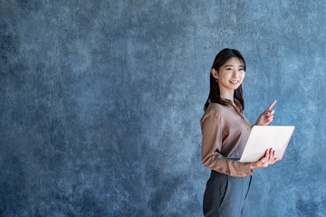 パソコンを持ち指差しをする女性