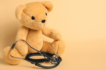 Pediatrics concept. Teddy bear with stethoscope on beige background, space for text