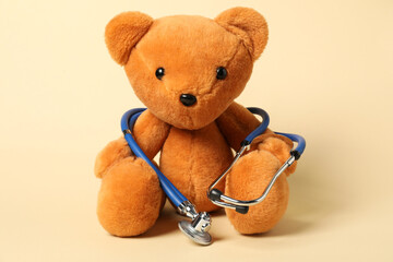 Pediatrics concept. Teddy bear with stethoscope on beige background