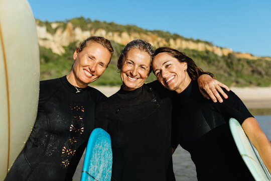 Three women enjoying a surfing holiday together on the beach - Powered by Adobe