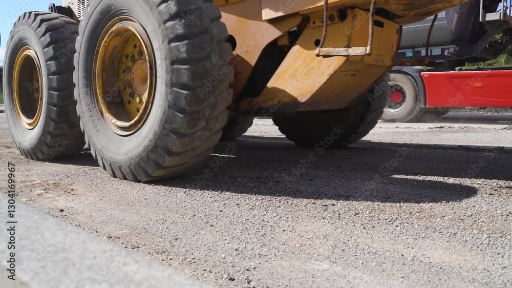 Fototapete low angle close-up shot of motor grader spreading gravel to create smooth, level foundation for new 