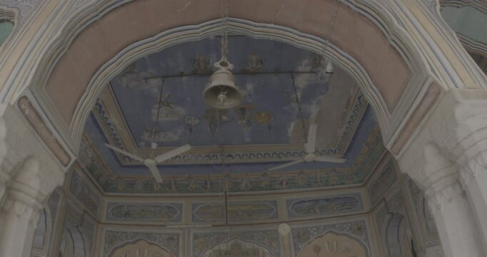 Close-up View on Bell Hangs At Entrance To Temple Hanuman Temple In Jaipur, India. Ungraded C LOG 2 Frescoes Decoration Walls. Sita And Rama With Sun And Moon On Background. Life Story Of Rama, Sita