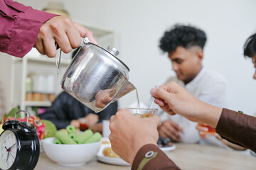 Muslim Man Pouring Tea To Break Fast During Ramadan Feasting Month at Dining Table
