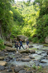 Fototapeta premium group of young asian standing on the rock while hiking and trekking in tropical nature