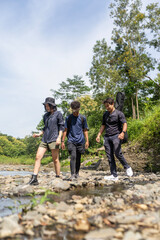 group of young asian trekking and hiking on rocky river stream
