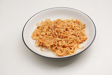 Indonesian fried noodles named Indomie, topped with fried onions, served on a white plate.