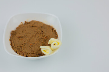A white plate with liver pate and pieces of butter stands on a white background on the left with space for text. The concept of healthy food, a healthy snack. High quality photo