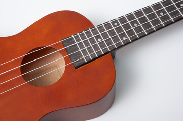 Fototapeta premium Ukulele made of natural wood of dark color photographed on a white background.