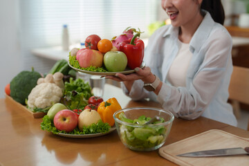 Woman holding plate of fresh fruits and vegetables promoting healthy eating