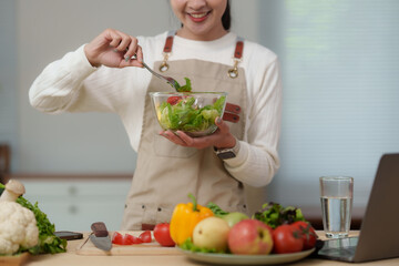 Smiling food blogger preparing healthy salad in her kitchen