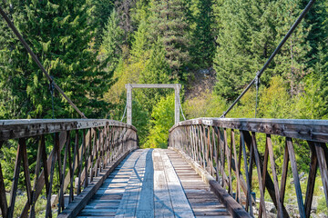 An old wood suspension bridges crosses the Lochsa River  on the Eagle Mountain Trail near Powell Junction, Idaho, USA