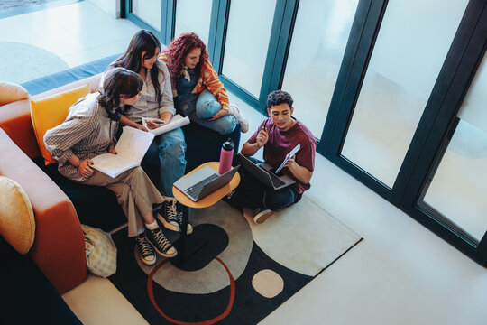 Informal library study session with diverse students collaborating and brainstorming ideas in a cozy corner