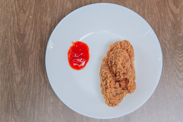 Crispy fried chicken with sauce on the side, on a white plate looking delicious.
